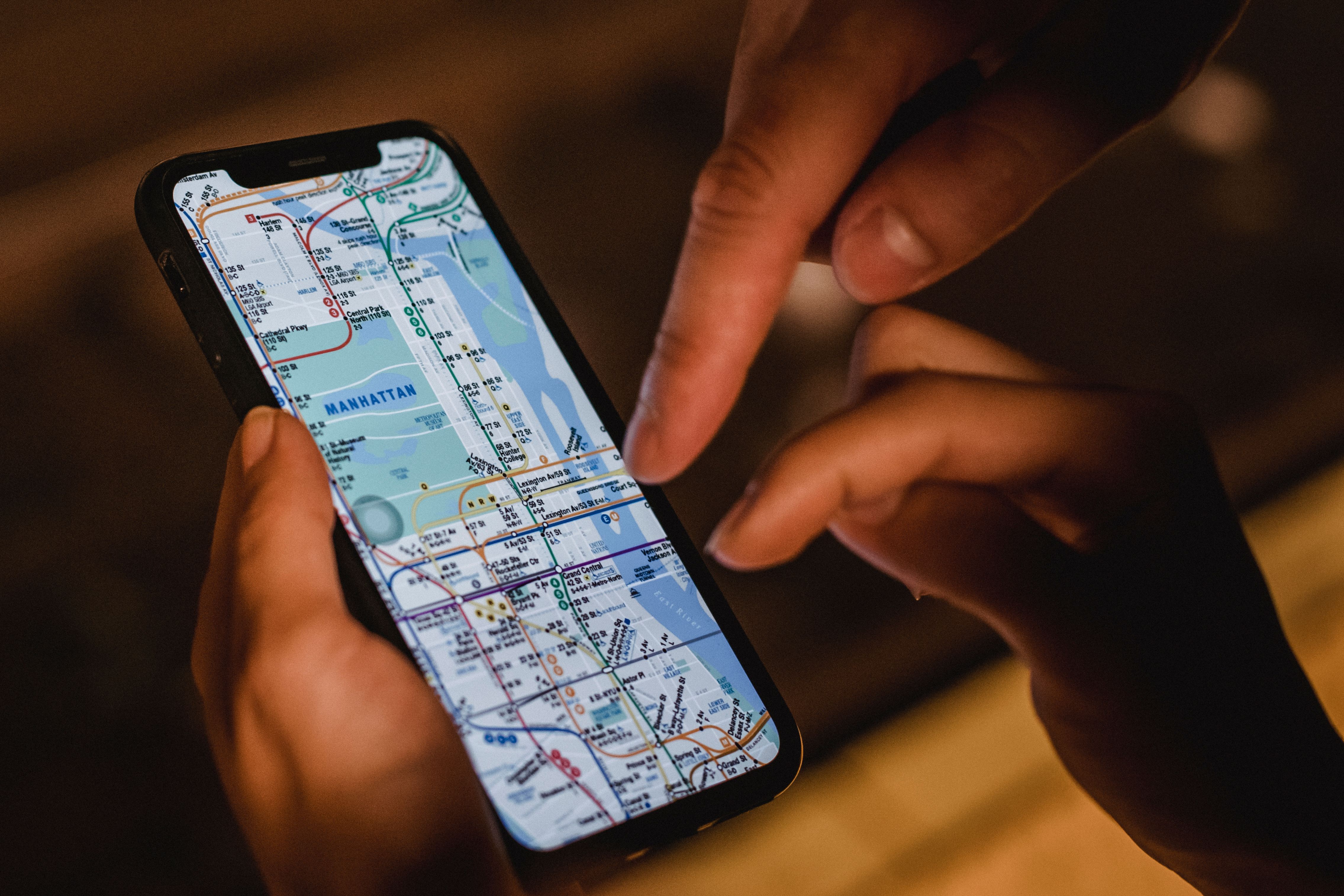 A couple checking a city map on a smartphone while standing on a dark urban street.