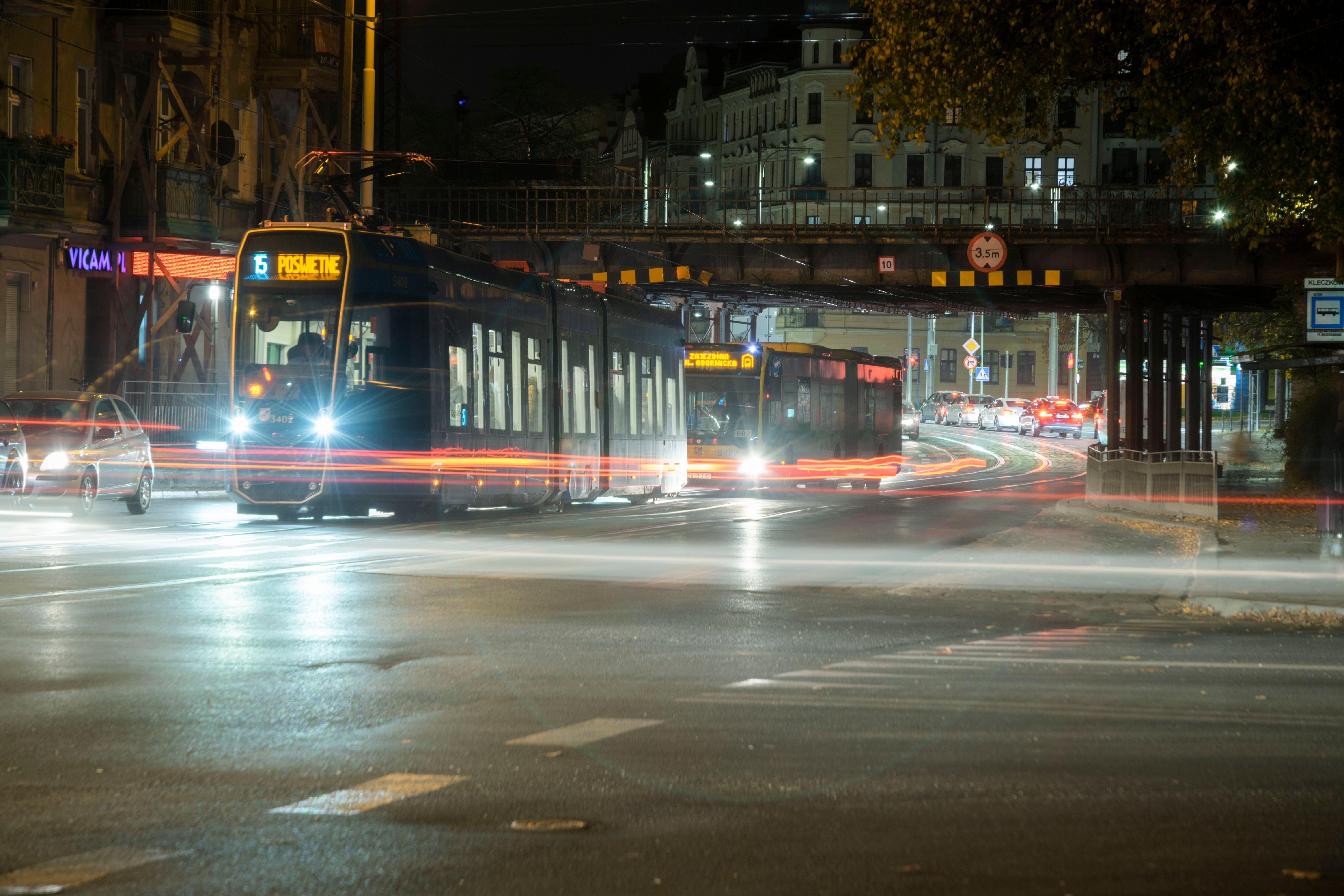 A tram traveling through a busy city street at night, representing public transportation after dark.